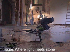A person crouching next to an object in a room with water on the floor